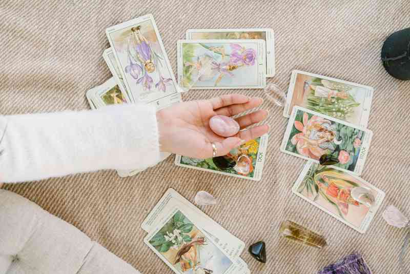 Cartas del Tarot esparcidas sobre una mesa, junto a cristales que limpian energéticamente las cartas